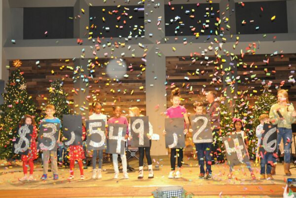 niños en la iglesia sostienen carteles con números mientras cae confeti
