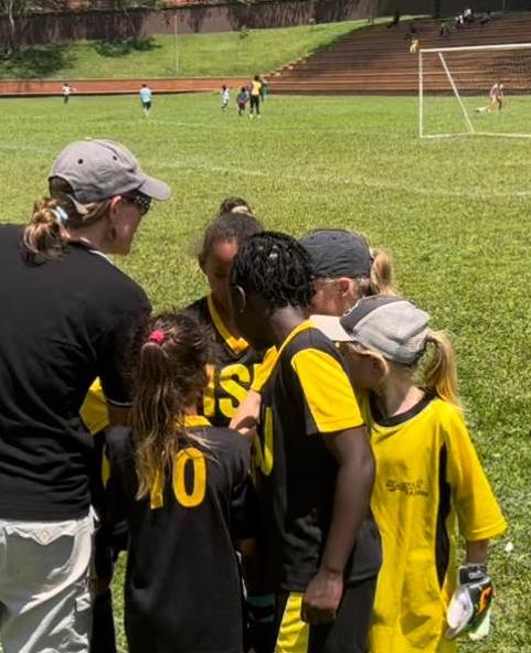entrenadora de fútbol en un grupo con jóvenes jugadores de fútbol con camisetas amarillas y negras