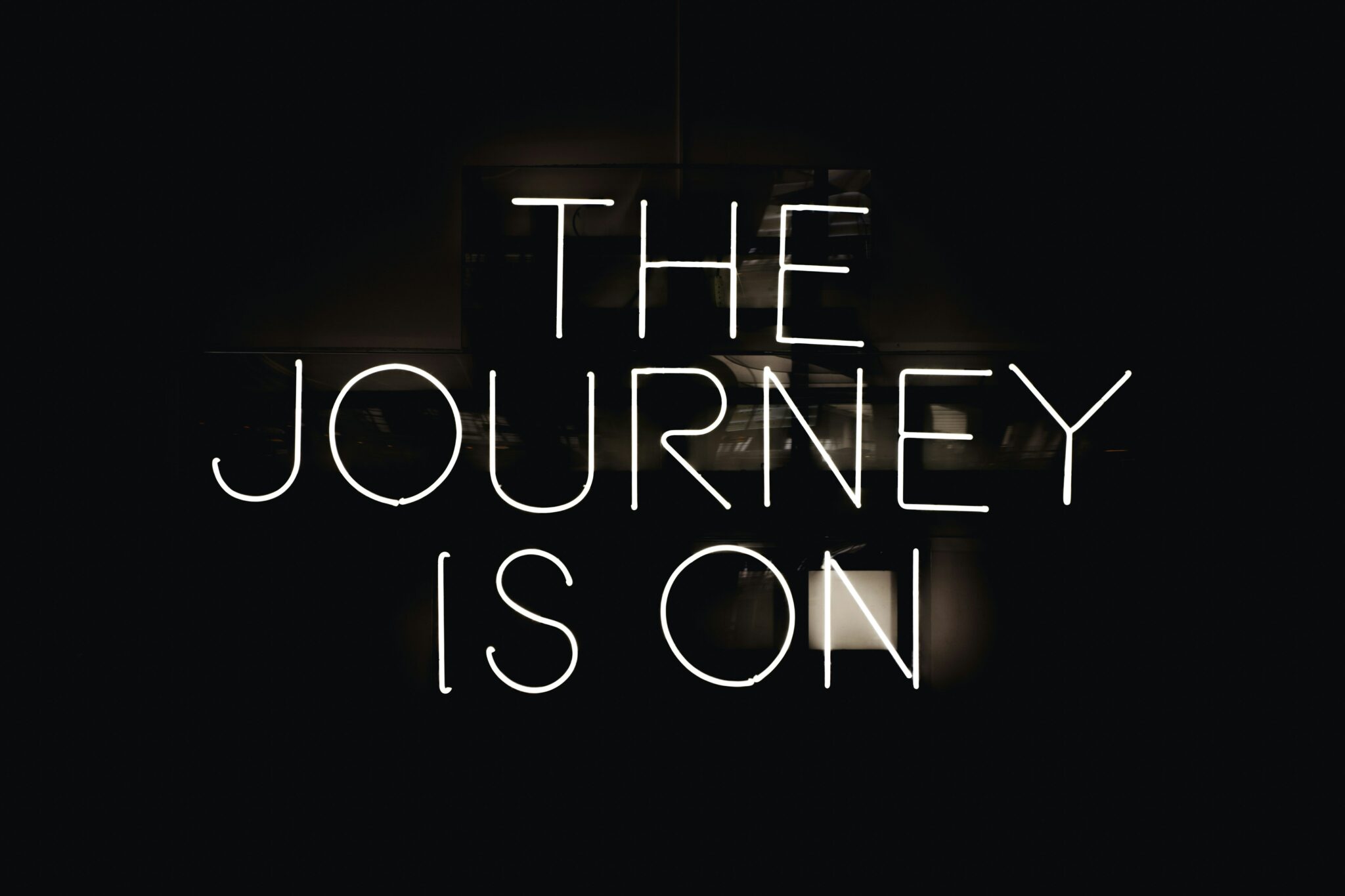 "the journey is on" white neon sign on black background